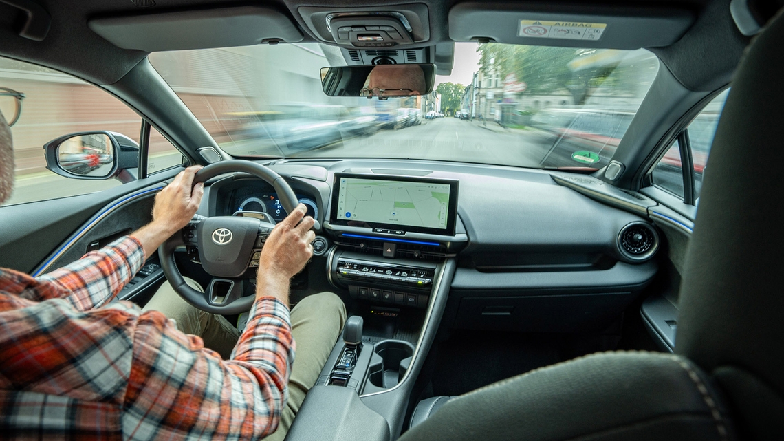 Toyota-C-HR-interieur-man-aan-stuur-rijdend-door-straten-dashboard